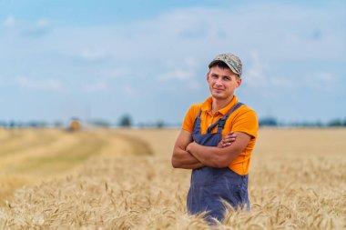Yakışıklı genç çiftçi tarlada sarı buğdayla el ele duruyor. Hasat mevsimi konsepti.