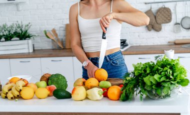 Diyet konsepti. Mutfakta sağlıklı yiyeceklerle güzel genç bir kadın vardı. Meyveler ve sebzeler.