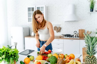 Diyet konsepti. Sağlıklı yiyeceklerle mutfağa yakın güzel bir genç kadın. Meyveler ve sebzeler.