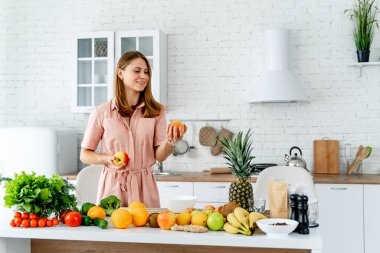 Diyet konsepti. Sağlıklı yiyeceklerle mutfağa yakın güzel bir genç kadın. Meyveler ve sebzeler.