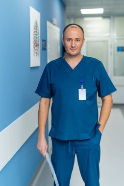 Klinikteki doktor. Doktor elinde belgelerle ayakta duruyor. Önlüklü adam..