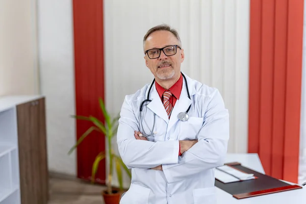 Portrait of a senior male doctor sitting at doctor\'s office and looking at camera. Thoughtful face of experienced doctor.