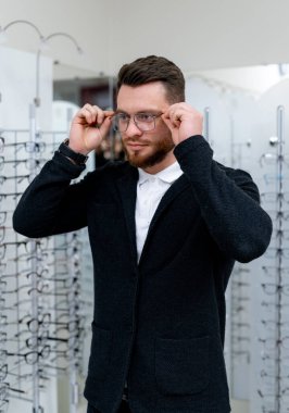 Gözlük seçiyorum. Optikteki müşteri. Seçici odaklanma. Adam aynaya bakıyor. Gözlükleri takın. Dükkanda geniş çeşitlilik.