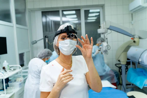 Professional ophthalmology doctor in surgery equipment before surgery operation. Young woman medic in operation theater with modern equipment.