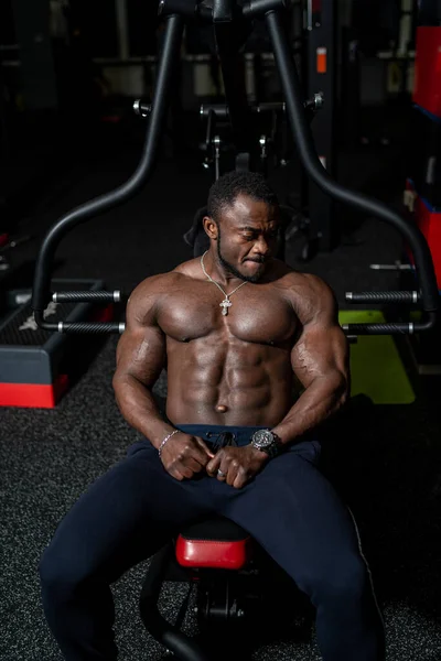 Muscular fitness trainer rests on sport bench after heavy training. Strong muscles and perfect abs. Closeup.