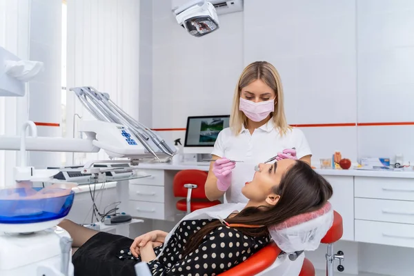 迷人的女牙医向坐在牙医椅子上的女病人解释治疗方法 概念性照片 — 图库照片