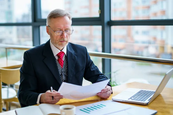 Przemyślany Biznesmen Średnim Wieku Garniturze Laptopem Stole Podczas Pracy Dokumentami — Zdjęcie stockowe