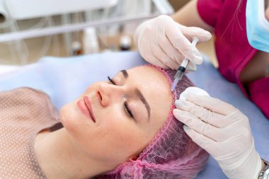 Alnına iğne. Seçici odaklanma. Kesilmiş fotoğraf. Güzellik kliniği. Güzellik uzmanı müşterinin yüzüne güzellik iğneleri yapıyor..