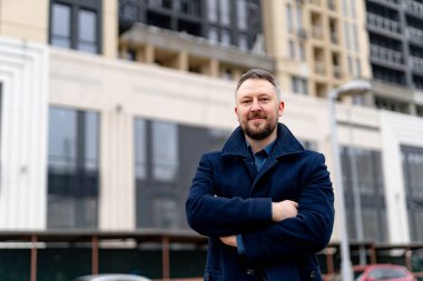 Sonbahar montlu çekici genç adam. Modern bir binanın önünde duran yakışıklı genç iş adamı..