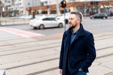 Gri ceketli ve koyu renk takım elbiseli şık bir adam.