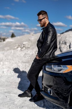 Çekici, zarif, ciddi bir adam iyi bir arabaya yaslanmış. Lüks otomobil içinde maço bir adam. 