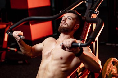 Spor malzemelerinin üzerinde mükemmel vücut kasları olan bir adam. Mükemmel vücutlu yakışıklı adama yandan bak..