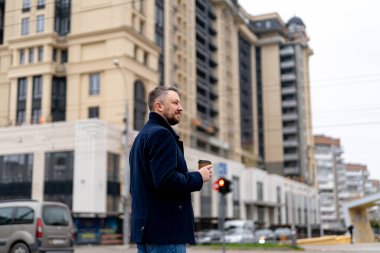 Adam elinde kağıt bardakla şehrin merkezindeki ofise doğru yürüyor. Sabahları kahve içmek. Yakın çekim..