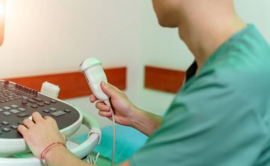 Bir doktor ultrason cihazlarını elinde tutar. Bir sonograf tarafından muayene. 
