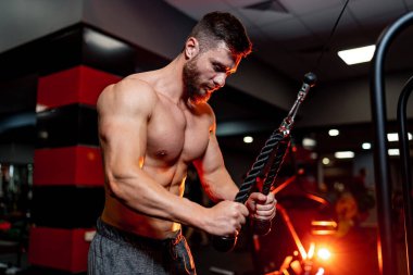 Spor salonunda sıkı çalışan kaslı vücut geliştirici. Atletik yakışıklı, çekici, çıplak gövdeli adam egzersiz yapıyor..