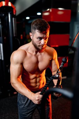 Vücut geliştirici, vücut geliştirme egzersizi yapıyor. Spor salonunda sağlıklı kaslı bir adam kaldırıyor. Güçlü bir erkek ağır bir eğitime sahiptir..