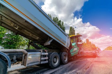 Ağır makineler yola çıktı. Yeni bir yol inşaatı. Asfalt dökmek için taze bitumen dökmeye özen gösterin. Seçici odak.