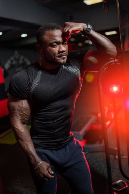 Eğitim için özel ekipmanların yanında siyah spor elbiseli yakışıklı Afro-Amerikan atletinin konsept fotoğrafı. Tatlı fitness eğitmeninin portresi.