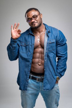 Modaya uygun kaslı adam kameraya bakıyor. Stüdyoda poz veren gözlüklü atletik erkek..