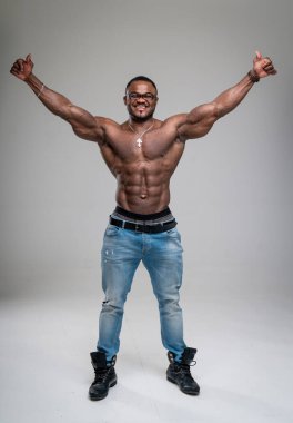 Stüdyoda kaslarını gösteren kaslı vücut geliştirici. Çıplak gövdesi olan yakışıklı atletik adam kameraya poz veriyor..