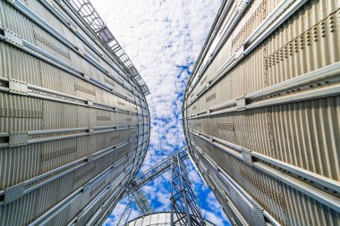 Toplu bitki deposu alçak açılı mavi gökyüzü. Tarım metalik mısır kulesi. Çelik buğday tankı. Metalik tank.