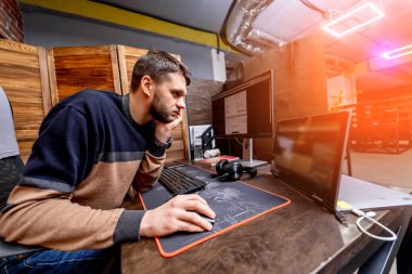 Bilgisayarla günlük giysiler içinde çalışan yakışıklı bir iş adamı. Modern ofiste çalışan bir işçi..