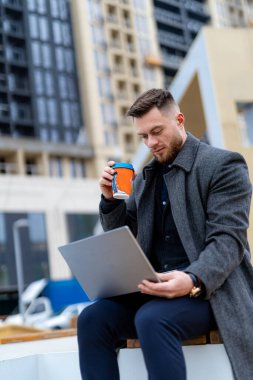 Laptopla çalışan yakışıklı bir adam. Genç başarılı iş adamı sokakta kahve molası verdi..