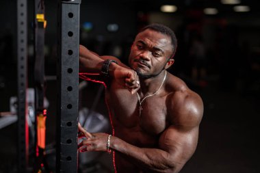 Spor salonunda kaslı bir adam ağırlık kaldırıyor. Aktif insanlar spor konsepti. Pompalı vücudu olan Afrikalı Amerikalı bir adam.