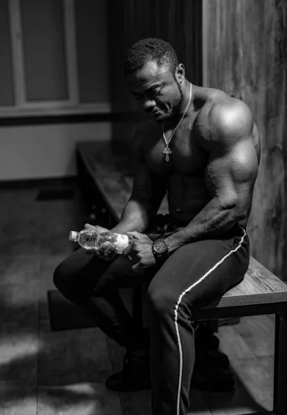 若いアフリカ系アメリカ人のスポーツマンがジムで水を飲む 筋肉の男アフリカのボディビルダー — ストック写真