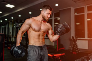 Ağırlık kaldıran güçlü bir sporcu. Çağdaş karanlık spor salonunda vücut geliştirici.