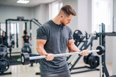 Spor salonunda atletik fiziksel adam eğitimi. Spor malzemeleriyle çalışan yakışıklı bir erkek..