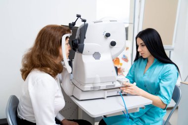 Optimetri kavramı. Güzel bayan doktor, son sınıf öğrencisini özel ekipmanlarıyla muayene ediyor. Yakın çekim..