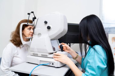 Esmer kadın opometrist, özel modern ekipmanlarla yaşlı kadına teşhis koyuyor. Sağlıklı gözler için güncel klinik. Yakın çekim..