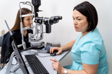 Deneyimli kadın doktor göz doktoru modern klinikteki genç bayanın görüşünü kontrol ediyor. Göz hekimliği kliniğinde doktor ve hasta..