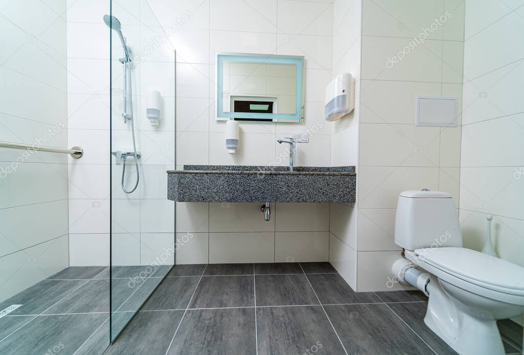 Bathroom in modern hospital. Grey and white colors in interior. Fully equipped commercial toilet in hospital. Closeup.