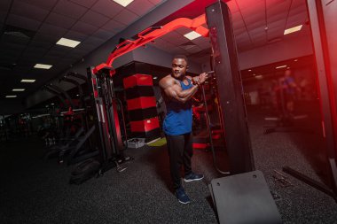 Spor salonunda çalışan sağlıklı yakışıklı bir adam. Kameraya poz veren güçlü kaslı güçlü vücut geliştirici..