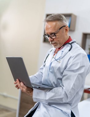 Karantina hastalarla hastanede çalışıyor. Bilgisayarla çalışan şık bir doktor..