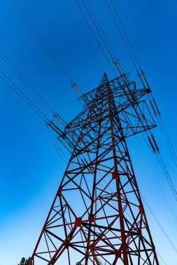 Mavi gökyüzünde büyük bir elektrik inşaat gölgesi. Elektrik dağıtımı için metal siluet mühendisliği.