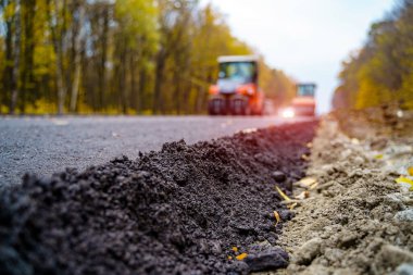 Asfalt Finişer makine yol yapımı sırasında çalışan işçiler. Yeni yol inşaat sitesinde çalışan yol silindiri görünümü Kapat