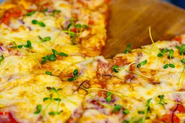 Kafe mutfağındaki paslanmaz çelik bir masada taze hazırlanmış pizza. Peynirli, pastırmalı ve sebzeli iştah açıcı sıcak pizza.