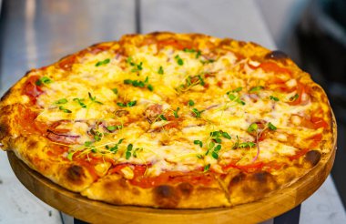 Masanın üzerindeki ahşap tezgahta taze pizza. Ahşap arka planda domates ve peynirli lezzetli pizza. Yakın plan.