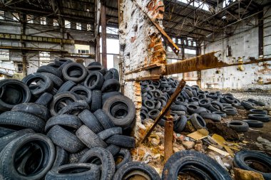 Bozuk fabrikada büyük bir araba lastiği yığını. Eski boş binanın içinde yerde bir sürü siyah lastik lastik vardı.