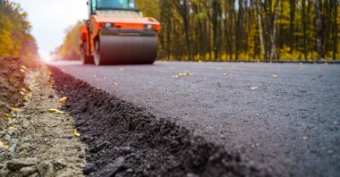 Yol silindiri yeni asfaltı dümdüz ediyor. Ağır titreşim silindiri asfalt döşeyip yol tamiri yapıyor. Seçici odak
