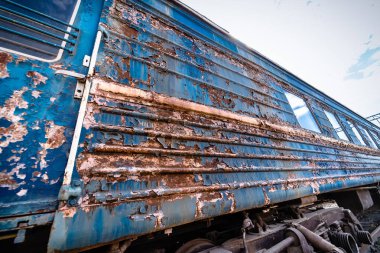 Terk edilmiş tren istasyonu. Paslı yıpranmış eski bir vagonun soyulmuş boyası. Mavi tren vagonu. Ulaşım kavramı