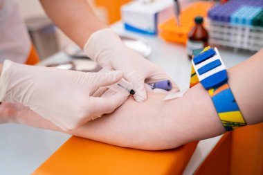 Elinde şırıngayla tanınmayan bir doktor test için kan alıyor. Bir kolun seçici bir kısmına odaklan. Klinik arkaplan