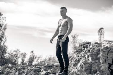 Dışarıda poz veren kaslı yakışıklı bir adam. Güçlü üstsüz vücut geliştirme eğitimi..