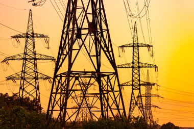 Sanayi elektrik kulelerinin arka planındaki iletim hatları. Gün batımında yüksek voltajlı elektrik kuleleri.