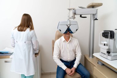 Kadın optometrist hastanedeki erkek hasta için görüş testi yapıyor. Optalmoloji kliniğindeki modern ekipmanlar. Yakın çekim.