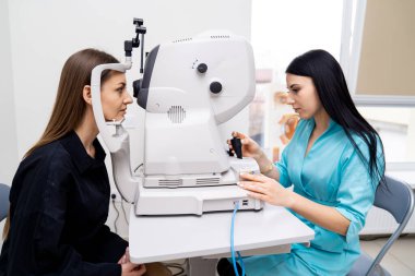 Görüşü test ederken refraktometre kullanan kadın optometristin portresini kapat. Klinikteki kadın hasta. Belini kaldır.