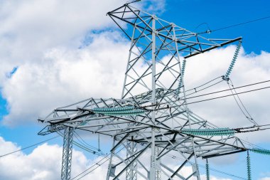 Elektrik tedarik istasyonunun görüntüsü. Yüksek voltajın koyu gölgesi. Mavi gökyüzü arkaplanına karşı yüksek voltaj sütunları